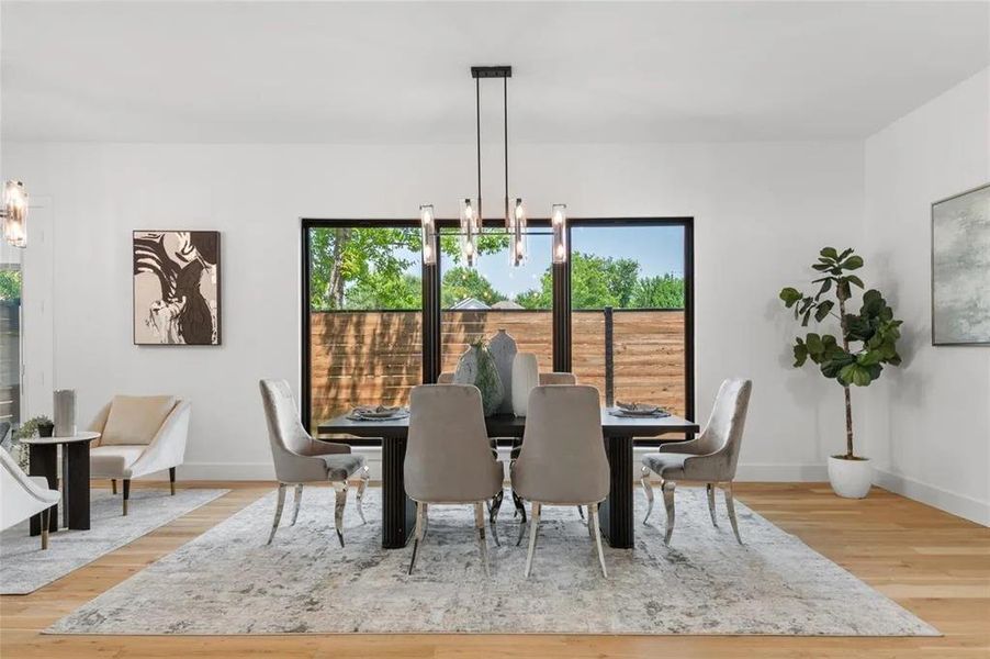 Dining area featuring light wood-finish flooring, white walls, and a contemporary linear chandelier Dining area featuring light wood-finish flooring, white walls, and a contemporary linear chandelier