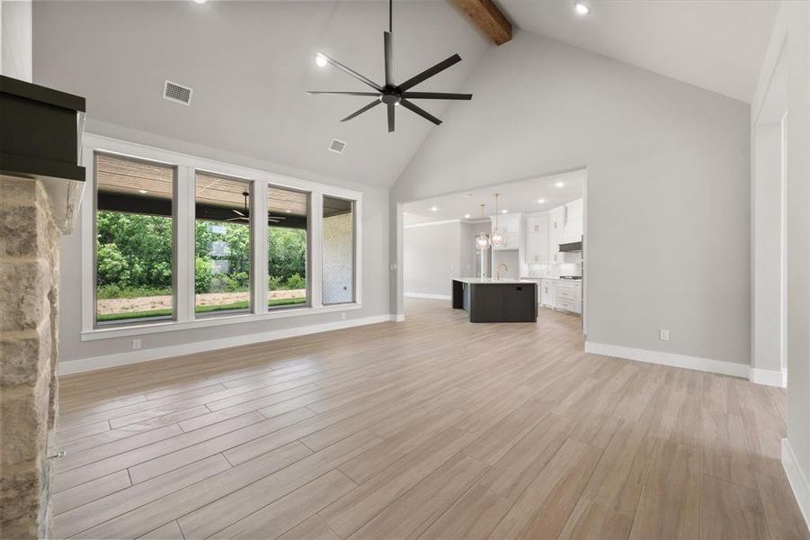 Spacious living area featuring vaulted ceilings with exposed wood beam, recessed lighting, and a contemporary ceiling fan