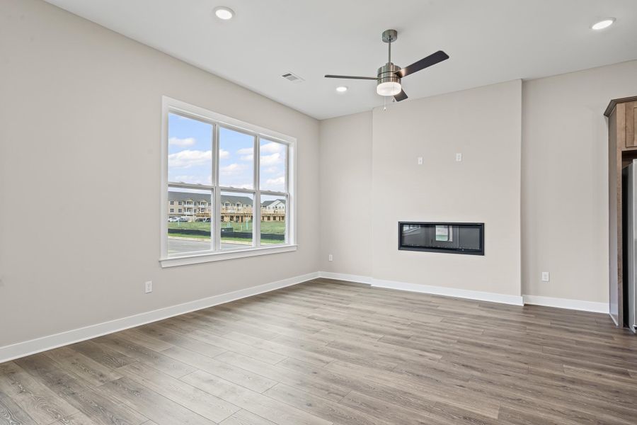 Unfurnished living room with light wood-type flooring, a glass covered fireplace, recessed lighting, and ceiling fan