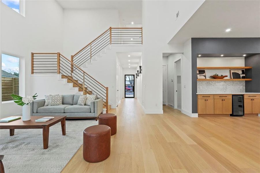 Living area with light wood finished floors, wine cooler, a high ceiling, and recessed lighting