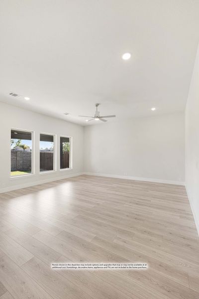 Empty living room with light wood floors, ceiling fan, recessed lighting, and backyard-facing windows Empty living room with light wood floors, ceiling fan, recessed lighting, and backyard-facing windows