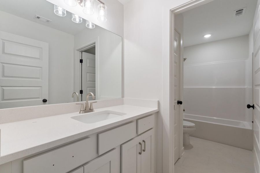 White vanity with brushed nickel hardware, integrated sink, and white countertop White vanity with brushed nickel hardware, integrated sink, and white countertop
