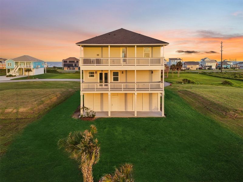 Sunset view of the rear elevation showcases both levels of expansive decks, lush backyard, and rare open green space—no rear neighbors, just peaceful bay breezes. Sunset view of the rear elevation showcases both levels of expansive decks, lush backyard, and rare open green space—no rear neighbors, just peaceful bay breezes.