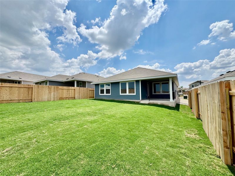 Rear view of house with a fenced backyard and a patio area
