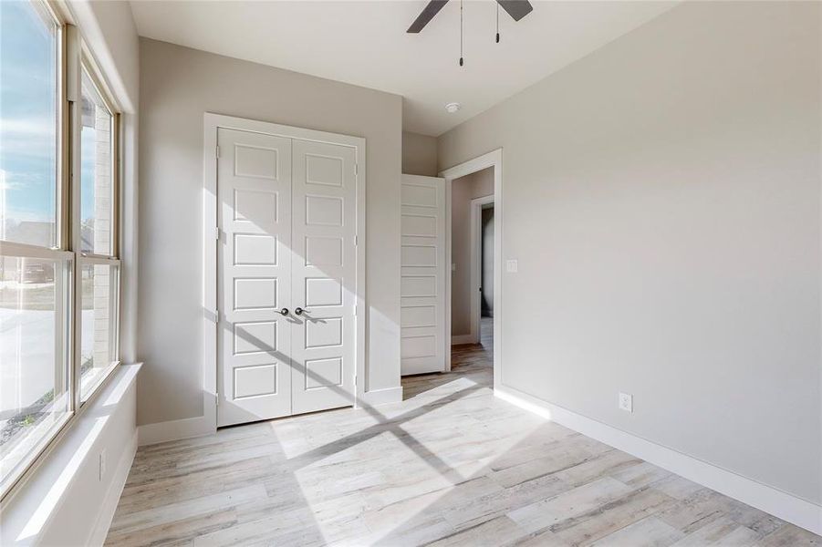 Unfurnished bedroom with a closet, light hardwood / wood-style flooring, multiple windows, and ceiling fan