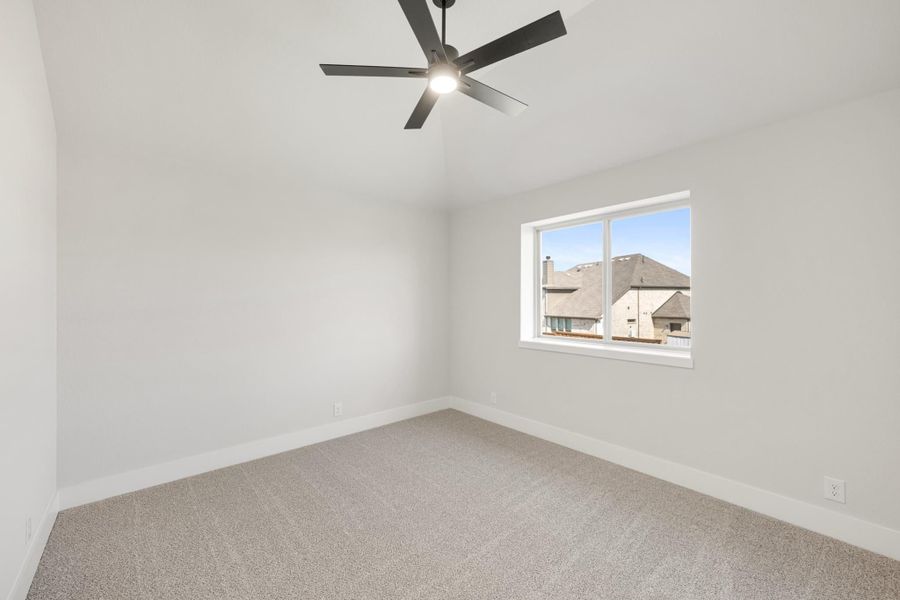 Empty bedroom with carpet flooring, black ceiling fan, and single window with neighborhood view