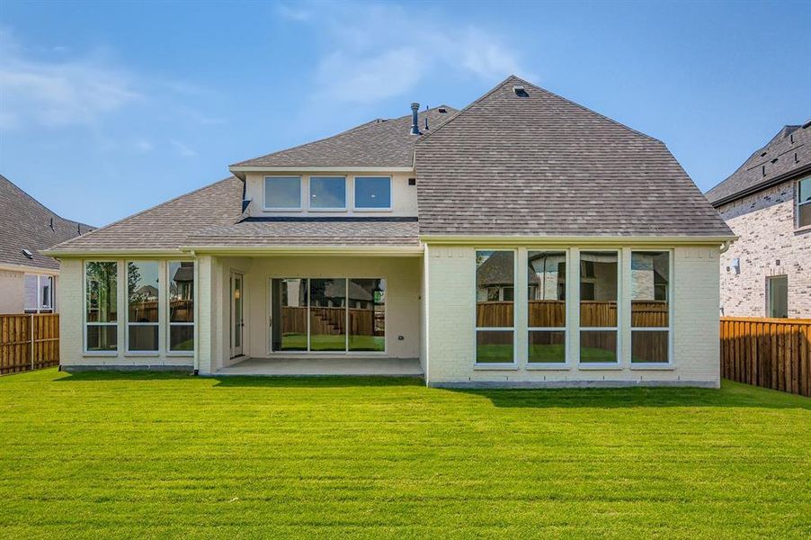 Rear view of house with a shingled roof, brick siding, and a patio area Rear view of house with a shingled roof, brick siding, and a patio area