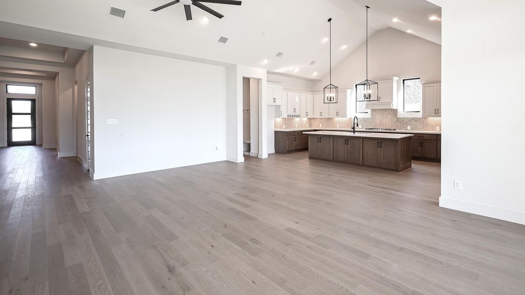 Kitchen featuring high vaulted ceiling, open floor plan, decorative backsplash, pendant lighting, and a kitchen island with sink Kitchen featuring high vaulted ceiling, open floor plan, decorative backsplash, pendant lighting, and a kitchen island with sink
