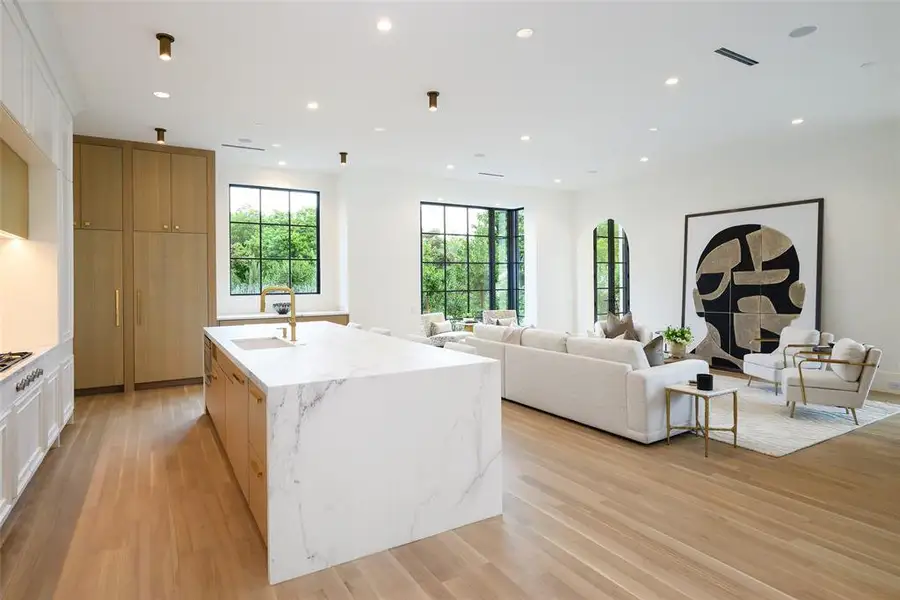 Kitchen featuring recessed lighting, white cabinets, light stone countertops, light wood-style flooring, and an island with sink Kitchen featuring recessed lighting, white cabinets, light stone countertops, light wood-style flooring, and an island with sink