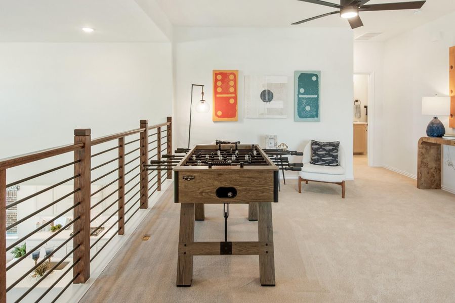 Upstairs loft game room with foosball table, wood railing overlooking lower level, and ceiling fan Upstairs loft game room with foosball table, wood railing overlooking lower level, and ceiling fan