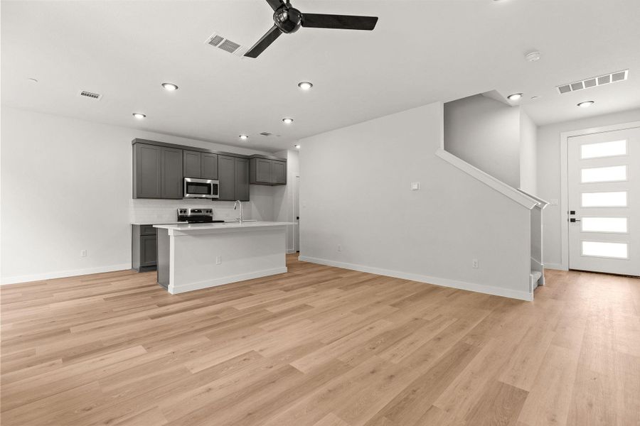 An open-concept living area with a kitchen island and sleek hardwood flooring creates an inviting atmosphere.
