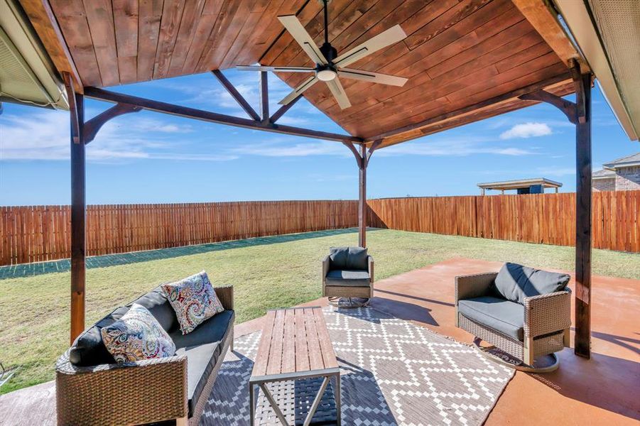 Fenced backyard featuring a ceiling fan, a patio, and an outdoor hangout area