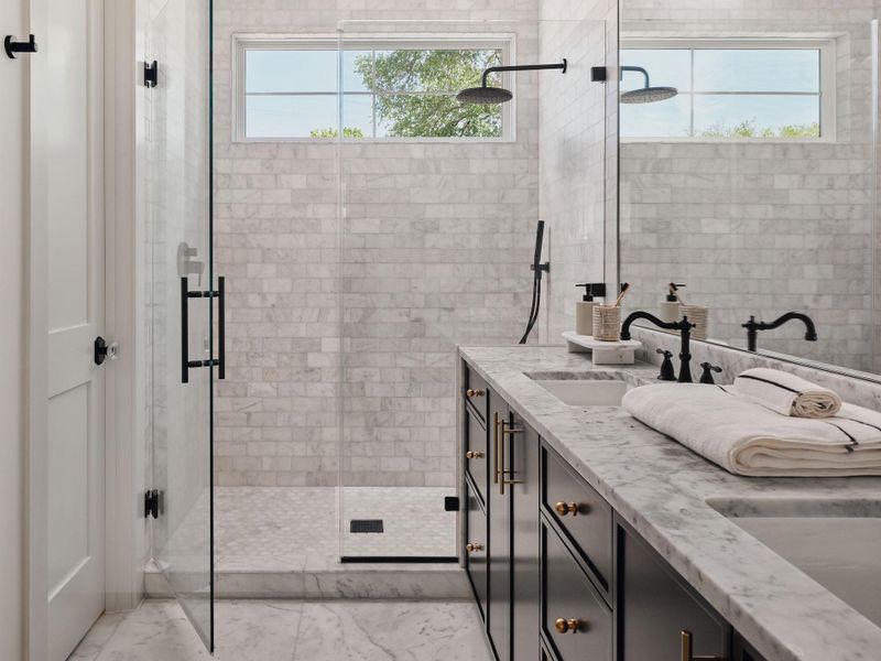 Bathroom with double vanity, a stall shower, and plenty of natural light