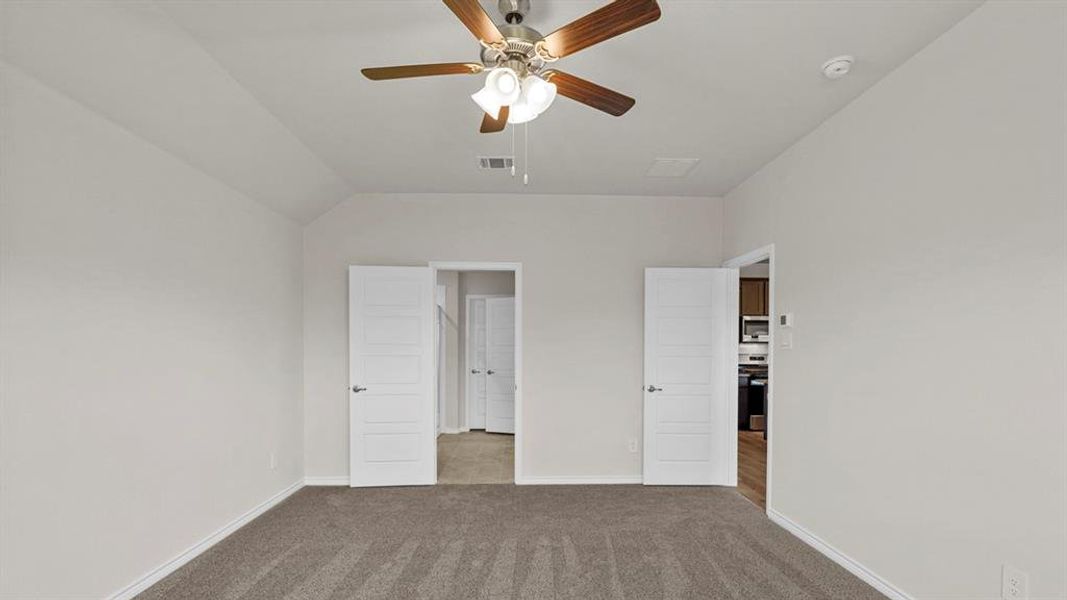 Spacious room featuring vaulted ceilings and neutral-toned carpeting