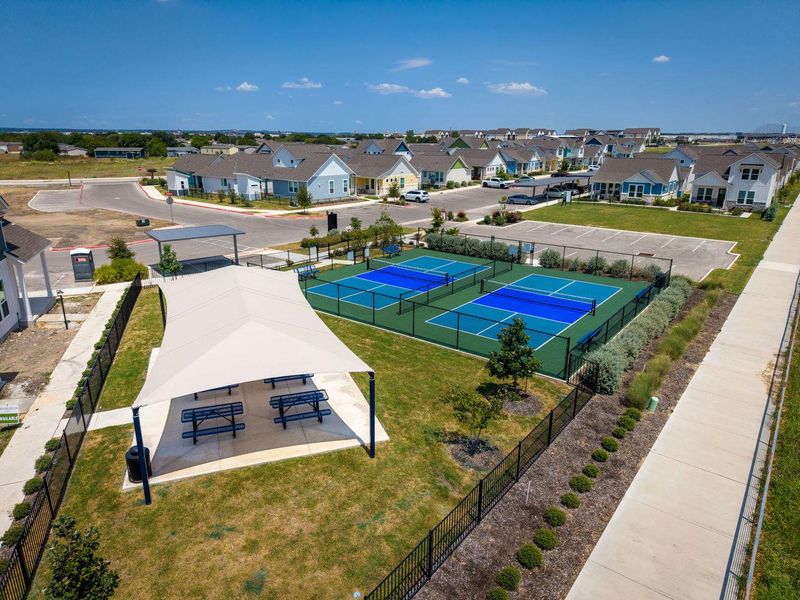 A vibrant community recreation area featuring outdoor sports courts and a shaded pavilion under open skies. A vibrant community recreation area featuring outdoor sports courts and a shaded pavilion under open skies.