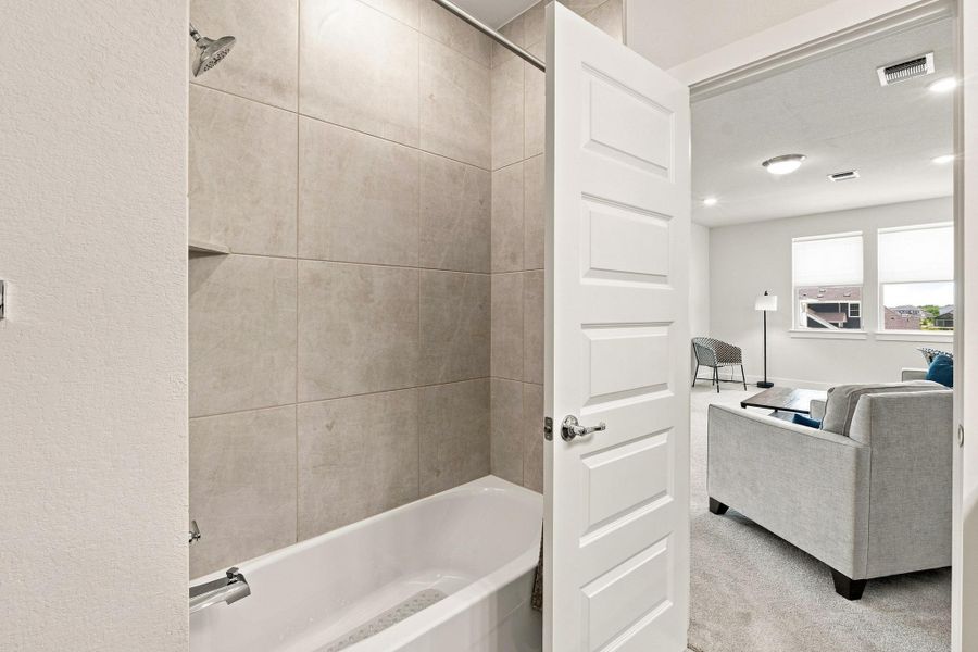 Full bath tub/shower combo showcasing Level 5 tile surround extended straight to the ceiling. Full bath tub/shower combo showcasing Level 5 tile surround extended straight to the ceiling.