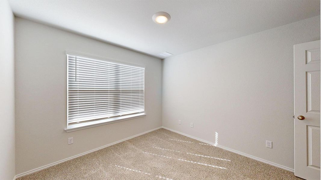 A well-lit bedroom with plush carpeting, ready for personalization.