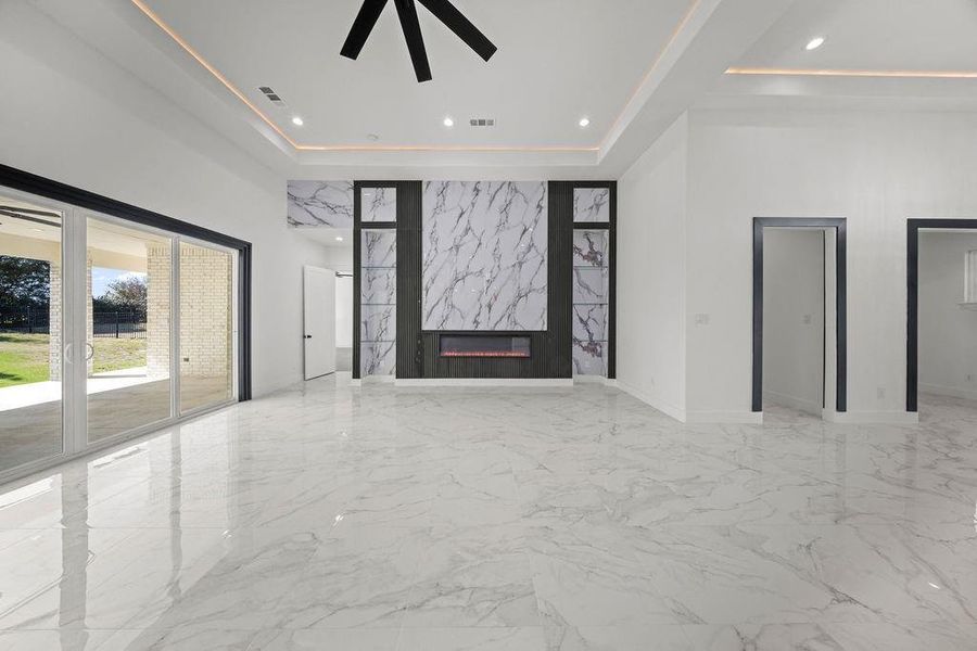 Foyer entrance with recessed lighting, a premium fireplace, light marble finish flooring, a ceiling fan, and a tray ceiling
