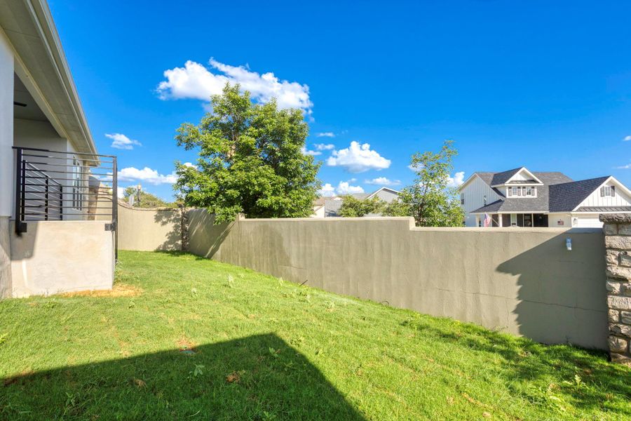 Expansive backyard featuring a sloped lawn and a perimeter wall Expansive backyard featuring a sloped lawn and a perimeter wall
