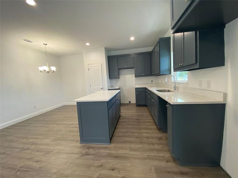 Kitchen with light wood-style floors, recessed lighting, a center island, light stone countertops, and decorative light fixtures Kitchen with light wood-style floors, recessed lighting, a center island, light stone countertops, and decorative light fixtures