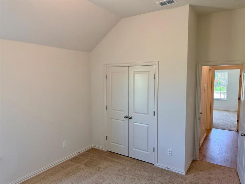 Room featuring a vaulted ceiling and neutral-toned carpeting