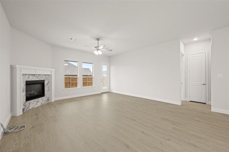 Unfurnished living room featuring light wood finished floors, a ceiling fan, and a fireplace