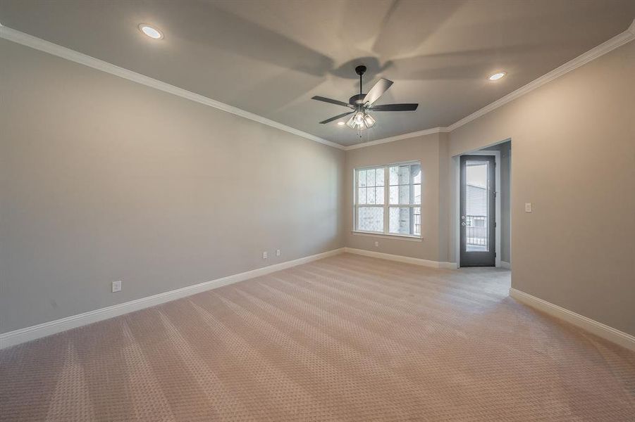 Spacious room featuring neutral carpet, crown molding, a ceiling fan, recessed lighting, and a large multi-pane window