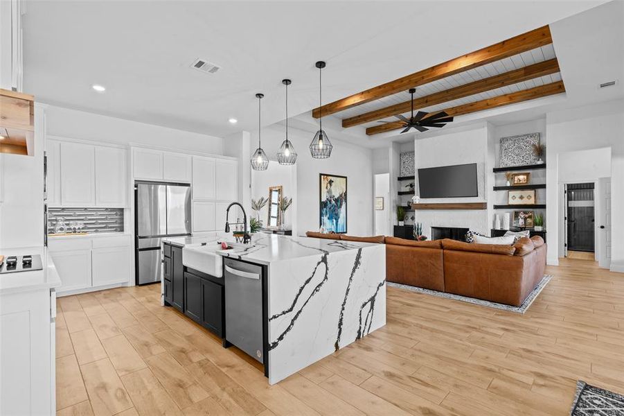 Kitchen with white cabinetry, light hardwood / wood-style flooring, an island with sink, and appliances with stainless steel finishes