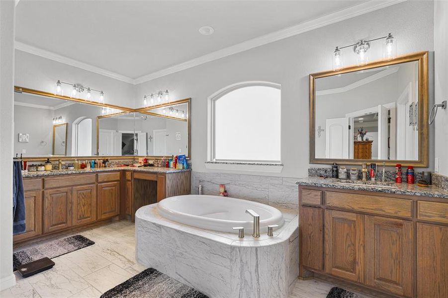 Bathroom with vanity, ornamental molding, and tiled tub