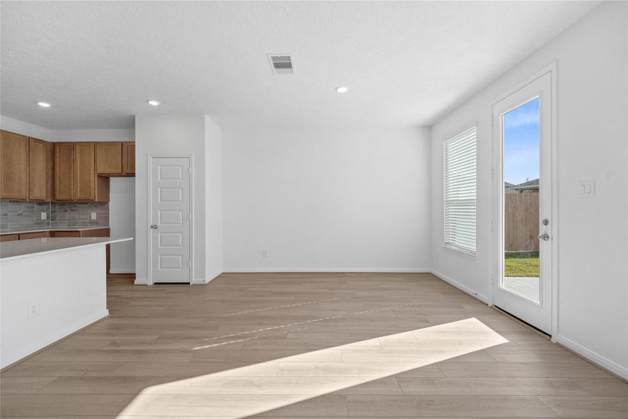 Create lasting memories around the table with family and friends in this inviting dining room! It showcases high ceilings, large windows with privacy blinds, access door to the back patio and yard, vinyl plank flooring, and recessed lighting for a warm and welcoming atmosphere.