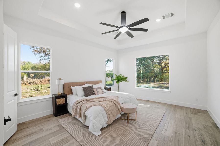 Bedroom with a tray ceiling, light wood-style flooring, recessed lighting, and ceiling fan Bedroom with a tray ceiling, light wood-style flooring, recessed lighting, and ceiling fan