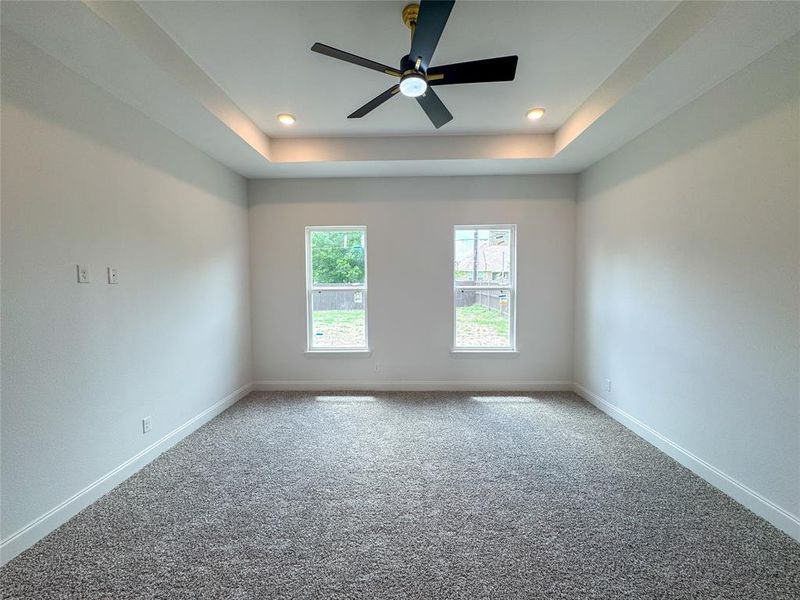 Carpeted spare room featuring a ceiling fan, baseboards, a tray ceiling, and recessed lighting Carpeted spare room featuring a ceiling fan, baseboards, a tray ceiling, and recessed lighting
