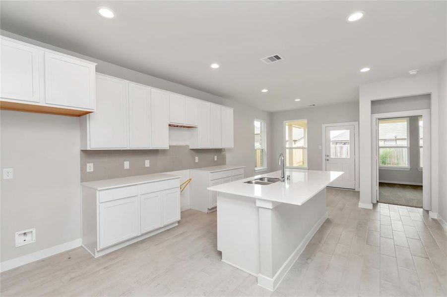 Discover another perspective of this stunning kitchen, generously appointed with an abundance of counter space. Sample photo of completed home with similar floor plan. As-built interior colors and selections may vary