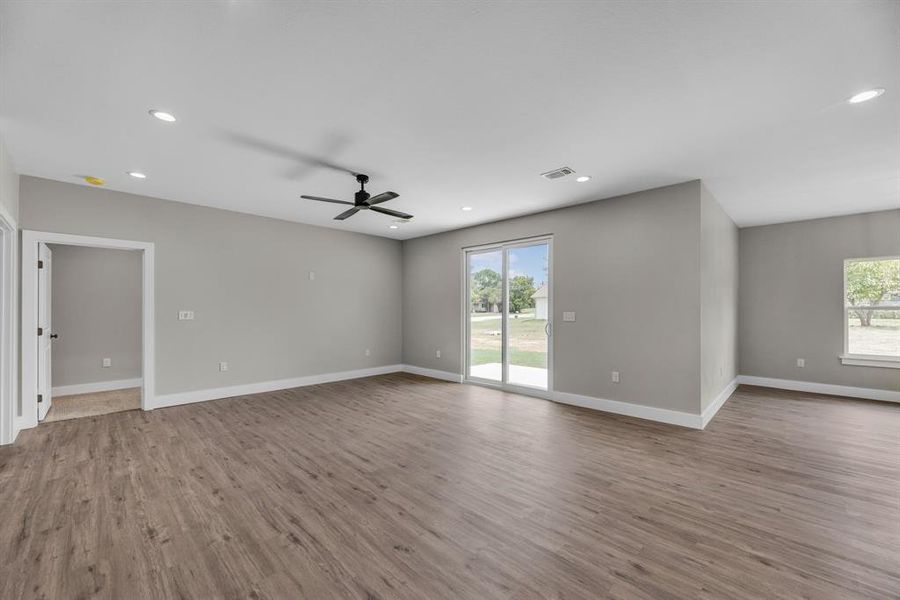 Empty room featuring wood-type flooring, plenty of natural light, and ceiling fan