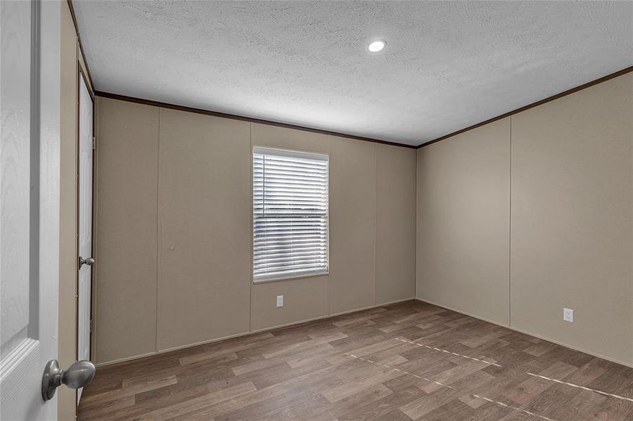 Empty room featuring a textured ceiling, crown molding, and hardwood / wood-style floors