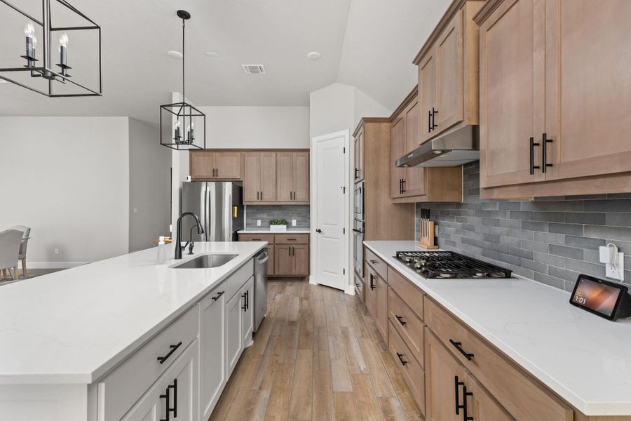 Kitchen featuring island with sink, pendant lighting, and sleek white stone countertops
