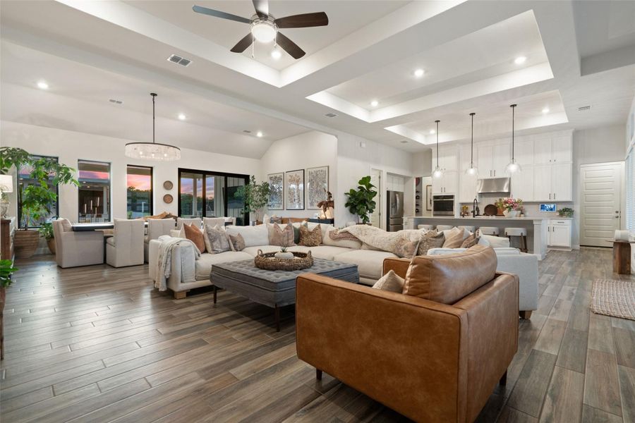 An open concept living area features soaring ceilings and wood plank flooring, seamlessly connecting the kitchen and dining spaces. An open concept living area features soaring ceilings and wood plank flooring, seamlessly connecting the kitchen and dining spaces.
