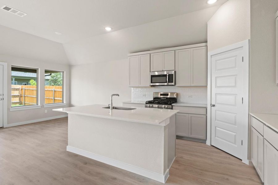 A well-appointed kitchen features a central island, gas range, and stylish stainless steel appliances.