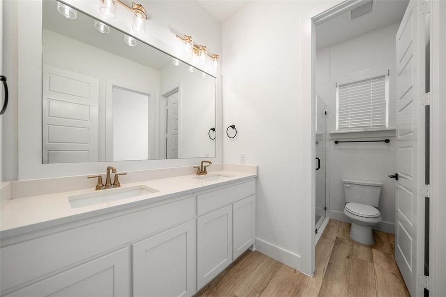 Full bathroom featuring double vanity, wood finished floors, and a shower stall