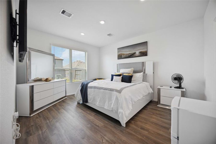 Primary bedroom with wood tile flooring and natural light