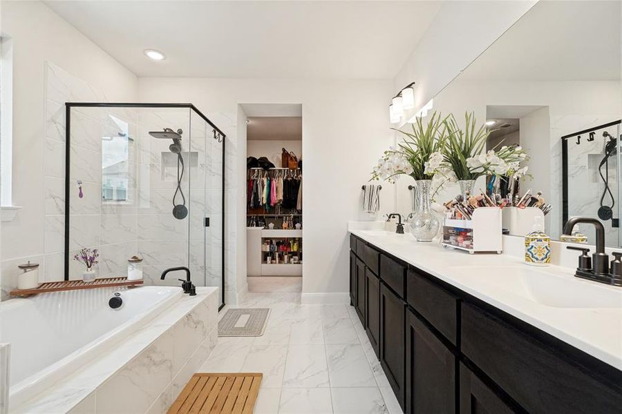Spacious bathroom featuring a built-in soaking tub, a large walk-in shower with black-framed glass enclosure, and a double vanity with ample counter space