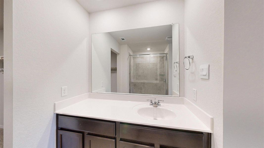 Bathroom vanity featuring a white countertop, undermount sink, and dark wood-finish cabinetry