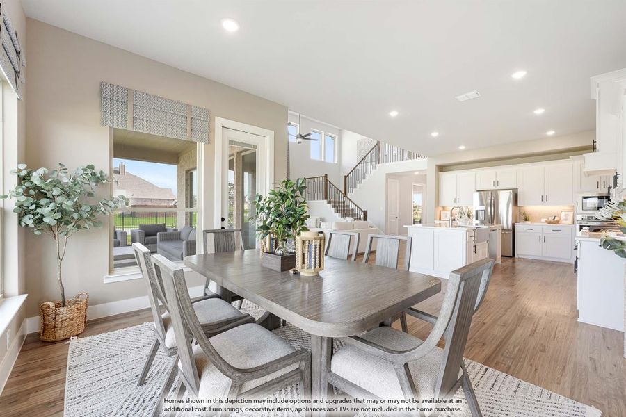 Open-concept dining area with gray wood table, six chairs, and view of white kitchen and staircase beyond