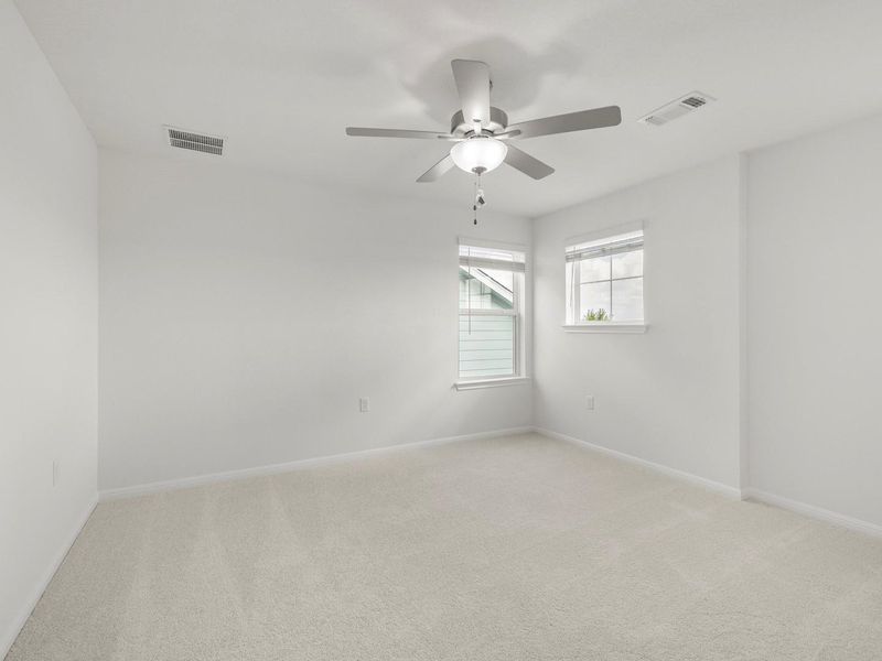 A spacious room offers ample natural light and a practical ceiling fan.