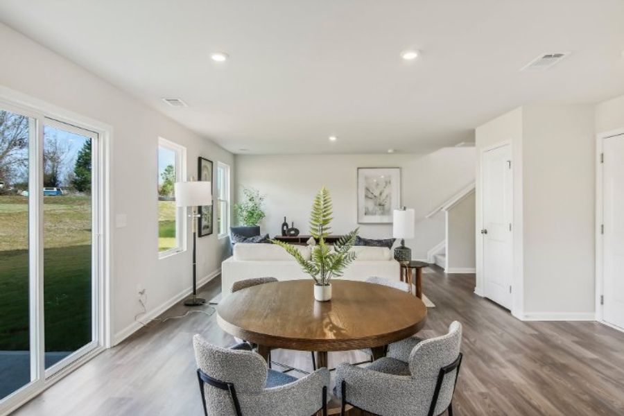 A dining room with a large glass door and a large table with chairs. A dining room with a large glass door and a large table with chairs.