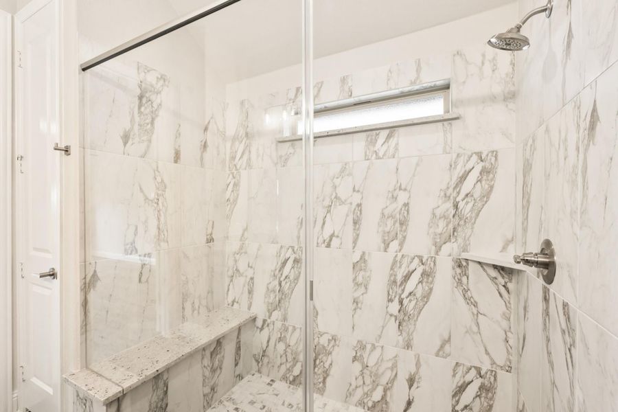Walk-in shower with marble tile walls, glass door, built-in bench, and overhead showerhead Walk-in shower with marble tile walls, glass door, built-in bench, and overhead showerhead