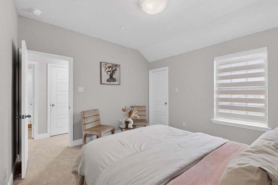 A bright room featuring light gray walls, carpeted flooring, and a window with horizontal blinds