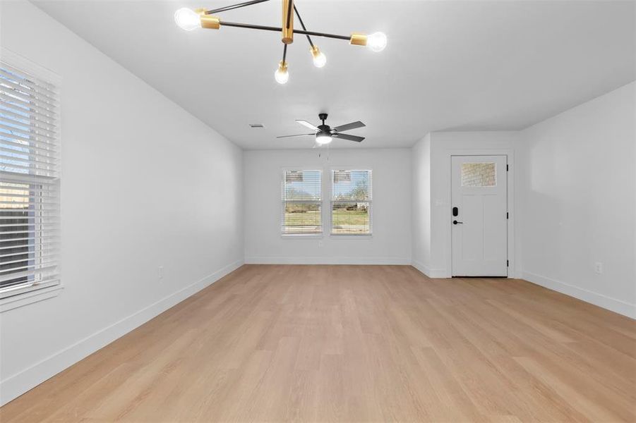 Unfurnished living room with light hardwood / wood-style flooring and ceiling fan with notable chandelier