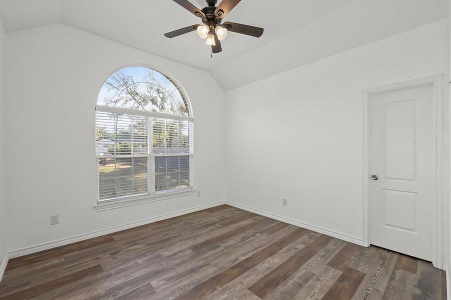 Unfurnished room with dark wood-type flooring, ceiling fan, and vaulted ceiling