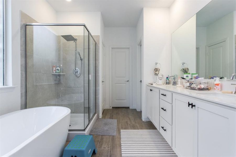 Bathroom featuring hardwood / wood-style floors, vanity, and plus walk in shower